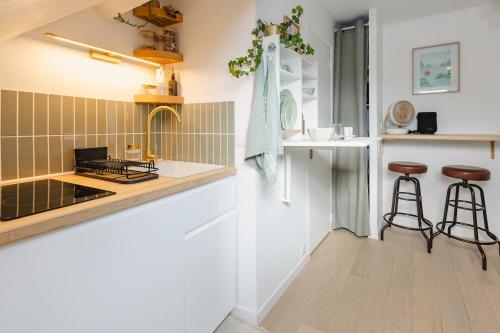 une cuisine avec un évier et un comptoir avec des tabourets dans l'établissement Le Petit Guéhenno - A quelques pas du centre-ville, à Rennes