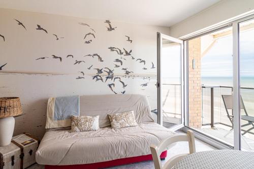 - une chambre avec un lit avec des oiseaux sur le mur dans l'établissement Résidence le Nautica - au pied de la plage, à Bray-Dunes