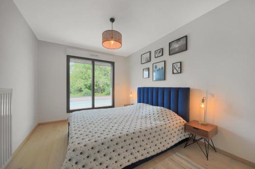 una camera da letto con un letto con testiera blu e una finestra di La Villa Sainghin - Piscine et Jacuzzi Privé a Sainghin-en-Mélantois