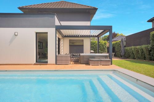une piscine devant une maison dans l'établissement La Villa Sainghin - Piscine et Jacuzzi Privé, à Sainghin-en-Mélantois