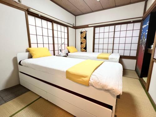 two beds in a room with windows at Ikebukuro no Yado detached house in Tokyo