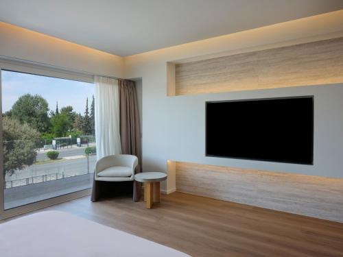 a bedroom with a tv and a chair and a window at Nur Riviera Aparthotel in Athens
