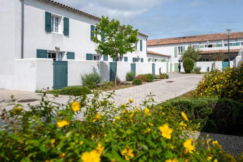 a white building with a courtyard with yellow flowers at Résidence Odalys Rêve d'île in Rivedoux-Plage