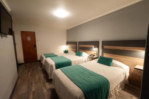 a hotel room with two beds with green and white sheets at Hotel Real in Linares