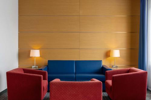 a living room with a blue couch and two chairs at Ramada by Wyndham Essen in Essen