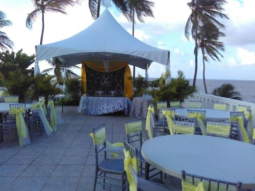 a table and chairs with a tent and the ocean at Blue Haven Hotel - Bacolet Bay - Tobago in Scarborough