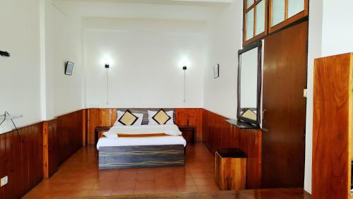 a small room with a bed and a mirror at Kalimpong Bungalow in Kalimpong