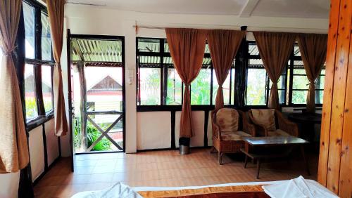 a room with windows and a table and chairs at Kalimpong Bungalow in Kalimpong