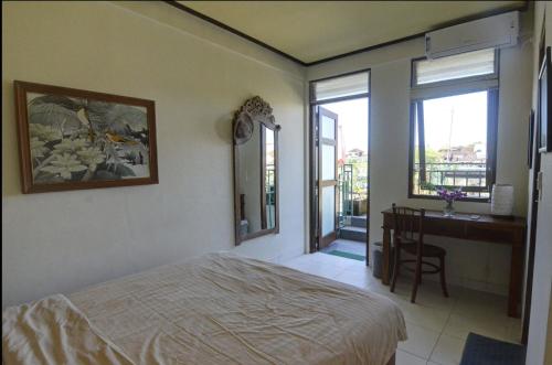 ヌサドゥアにあるRumah Gadang Bali Apartmentsのベッドと机と窓のある寝室