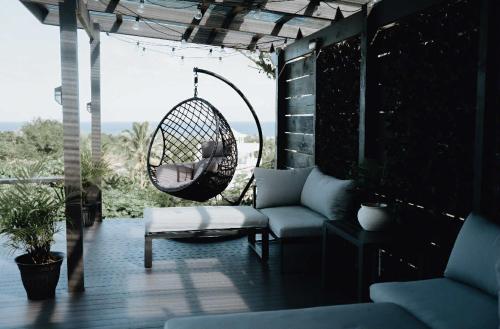 a patio with a swing and a chair and a table at VillaAmor in Arorangi