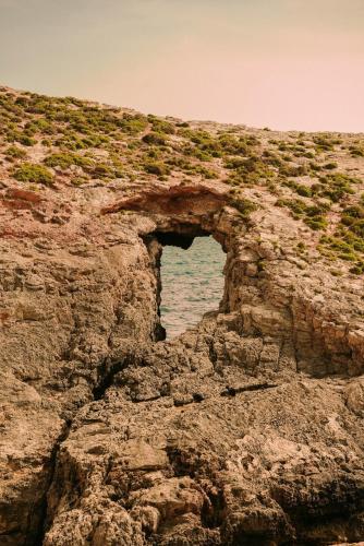 an arch in a rocky cliff near the ocean at 2BR Penthouse with Huge Terrace in peaceful Gozo by 360 Estates in Sannat