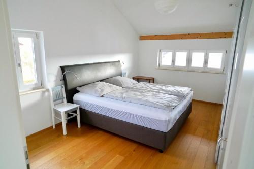 a bedroom with a bed and a chair in it at Ferienhaus Am Weitfeld - Ruheoase mit Garten & Bergblick nahe Salzburg in Ainring