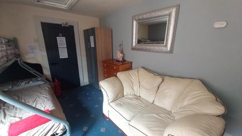a living room with a white couch and a mirror at Phoenix Nights Guest House in Barrow in Furness