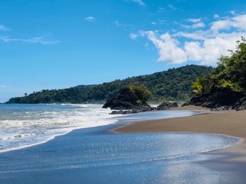 a beach with the ocean and mountains in the background at Hotel Destino del Pacifico - Bahia Solano in El Valle