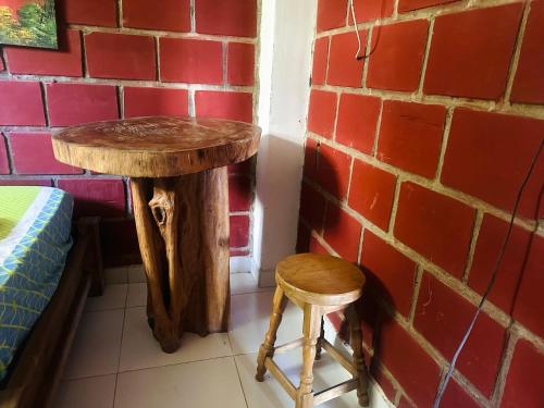 a table and two stools next to a brick wall at Hotel Destino del Pacifico - Bahia Solano in El Valle