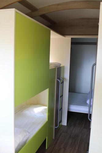 a room with two bunk beds with green walls at Camping Le Balcon de Chartreuse in Miribel-les-Échelles
