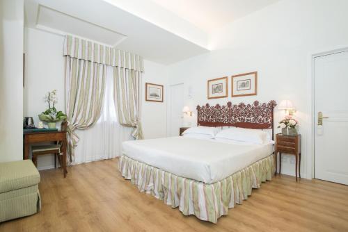 a white bedroom with a large bed and a window at Hotel Garden in Siena
