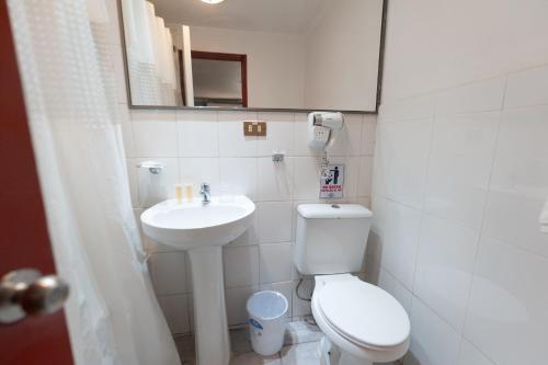 a small bathroom with a toilet and a sink at Hotel Real in Linares