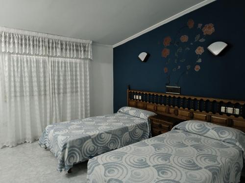 two beds in a bedroom with blue walls at Hotel Xacobeo in Outeiro