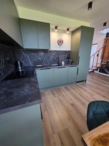 a kitchen with white cabinets and a wooden floor at Polana Jelenia Głowa in Wambierzyce