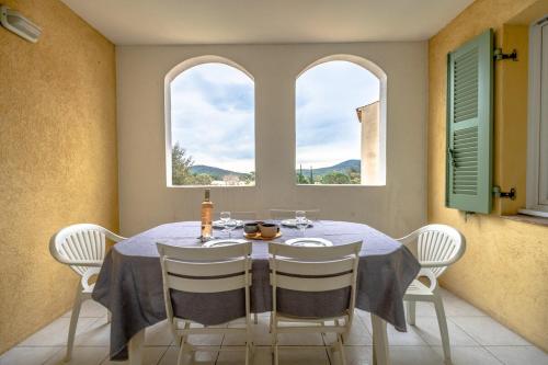 une salle à manger avec une table et deux fenêtres dans l'établissement Superbe Appartement climatisé dans résidence avec Piscine et parking, au Plan-de-la-Tour