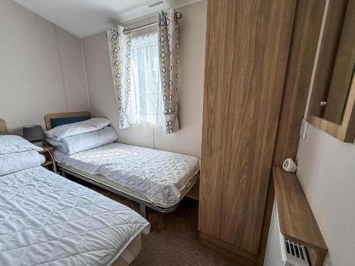 ハンスタントンにあるBeautiful Caravan With Decking At Manor Park In Hunstanton Ref 23042Bのベッドが2つと窓がある小さな部屋