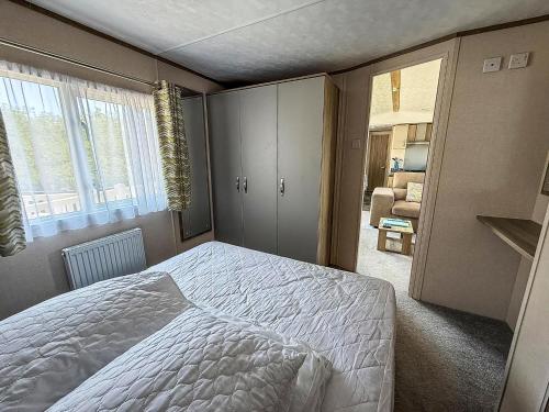 a bedroom with a white bed and a window at Beautiful 8 Berth Caravan At Heacham Beach In Norfolk Ref 21056C in Heacham