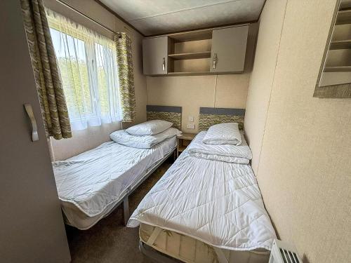 two beds in a hospital room with a window at Beautiful 8 Berth Caravan At Heacham Beach In Norfolk Ref 21056C in Heacham