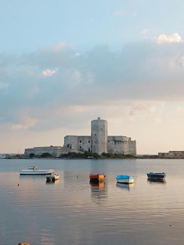 a group of boats in the water in front of a building at Sosta a colori in Trapani