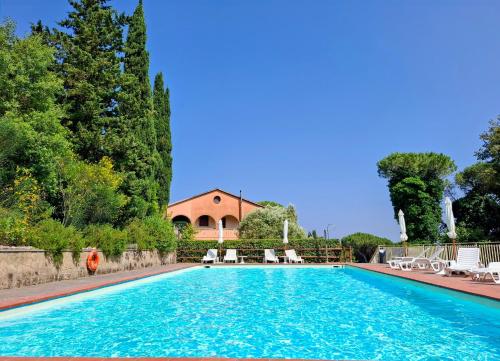 a swimming pool with chairs and a house in the background at La Casina di Laura&Gianni in Brancorsi