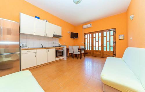 a kitchen with orange walls and white cabinets and a table at Apartments Vrisika-family apartment in Makarska