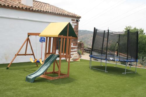 a playground with two swings and a slide at Molino Los Cardenes 1911 in Montoro