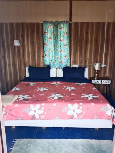 a bed with a red comforter with flowers on it at Corn Village Cottage in Lakhwār