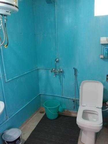 a blue bathroom with a toilet and a shower at Corn Village Cottage in Lakhwār