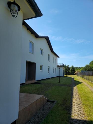 a white house with a yard and a fence at Noce i dnie in Białogóra