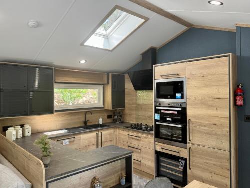 a kitchen with wooden cabinets and a skylight at Aberdunant Hall Holiday Park in Porthmadog