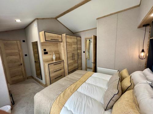 a bedroom with a large white bed and wooden cabinets at Aberdunant Hall Holiday Park in Porthmadog
