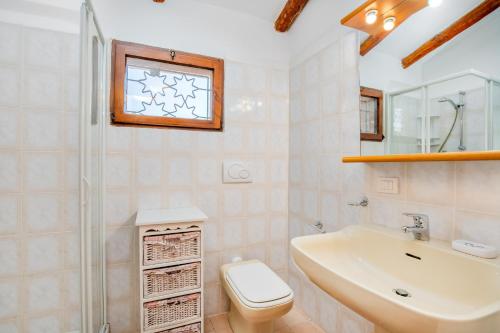 bagno con lavandino, servizi igienici e finestra. di Villetta Amelie a Baja Sardinia a Cala Bitta