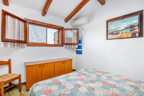 una camera da letto con un letto, una sedia e finestre di Villetta Amelie a Baja Sardinia a Cala Bitta