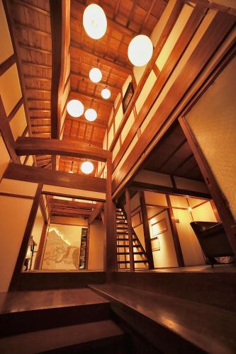 a large room with wooden ceilings and wooden stairs at Osakaya Hotel & SAUNA in Kaizuka