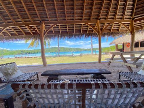 a pavilion with a table and chairs on the beach at Oeseli Beach Bungalow in Pulau Helihana