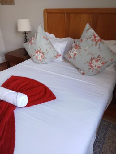 a white bed with pillows and a red towel on it at Kardinal guesthouse on 44 St Phillips street in Gqeberha