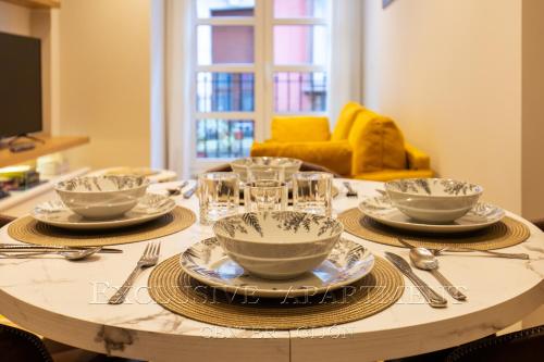 a table with plates and glasses on top of it at Exclusive Apartment Center Gijón in Gijón