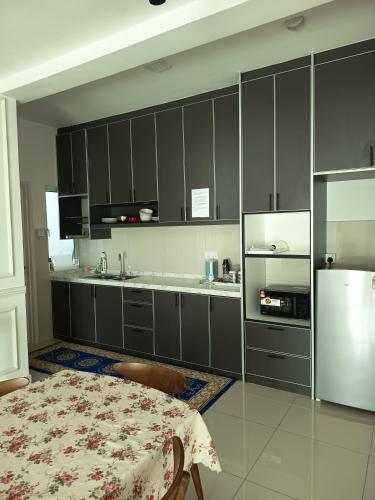 a kitchen with gray cabinets and a table and a refrigerator at CP11 Putrajaya strictly 6pax and 2cars in Putrajaya