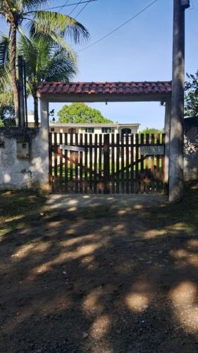 a wooden fence in front of a house with a tree at Casa Recanto do Vale in Guapimirim