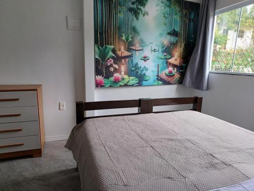 a bedroom with a bed and a painting on the wall at Casa Recanto do Vale in Guapimirim