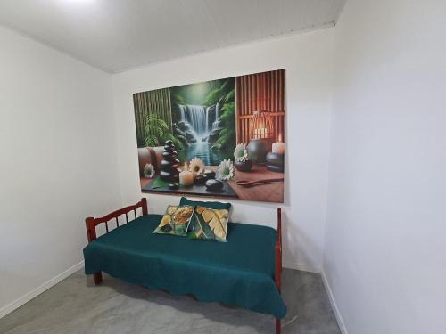 a bed in a room with a painting on the wall at Casa Recanto do Vale in Guapimirim