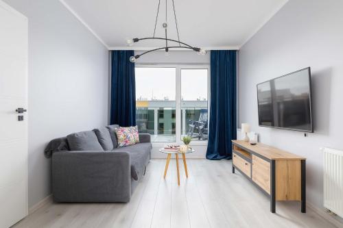 sala de estar con sofá gris y TV en Przestronny Apartament w Zielonej Okolicy Parking by Noclegi Renters, en Sosnowiec
