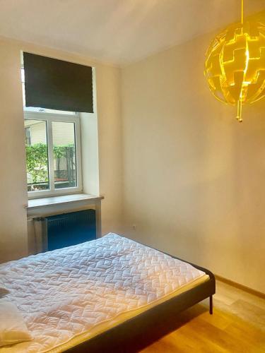 a bedroom with a bed and a window and a chandelier at Cosy 2-room apartment center Self check-in in Rīga