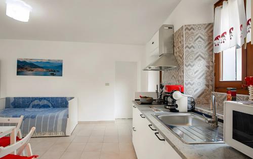 a white kitchen with a sink and a bed at La piccola Lami in Intra